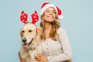 Young owner woman in casual clothes Santa hat hug cuddle embrace best friend pet retriever dog look...