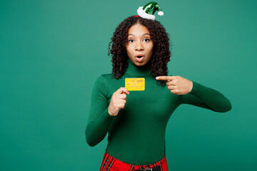 Merry little kid teen girl wear hat casual clothes posing hold point finger on credit bank card...