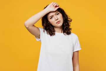 Young sad sick tired exhausted Caucasian woman wear white blank t-shirt casual clothes put hand on forehead look camera isolated on plain yellow orange background studio portrait. Lifestyle concept.