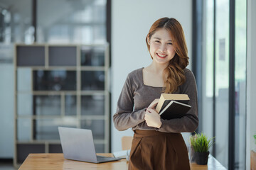 young asian woman holding a book in hands and education, lifestyle of woman studying. 