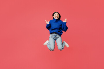 Full body young happy woman of Asian ethnicity she wear blue sweater casual clothes jump high look camera spread hands isolated on plain pastel light pink background studio portrait Lifestyle concept