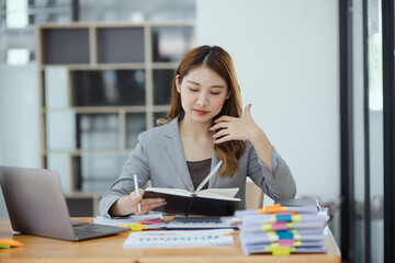 Businesswoman working with stack of documents papers and laptop sitting at office desk.