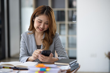 Accounting asian woman use smartphone and laptop at office desk in office, Accounting businesswoman online working concept.