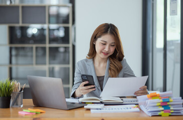 Accounting asian woman use smartphone and laptop at office desk in office, Accounting businesswoman...
