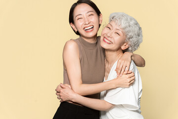 アジア人親子ポートレート、寄り添い笑っている/スタジオ撮影黄色背景	