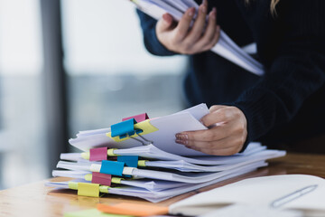 Asian businesswoman working with stack of documents papers at office desk.