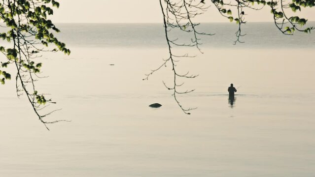 Baltic Sea in the spring. A fisherman in waders fishing for sea trout and garfish. 