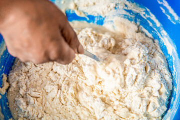 Woman kneading dough by hand yeast dough. Preparing dough, mixing ingredients. Woman stirs around spoon in bowl flour. Making sourdough from scratch