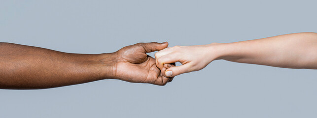 Giving a helping hand to another. Woman and african woman hand. Black and white human hands. African and caucasian hands - obrazy, fototapety, plakaty
