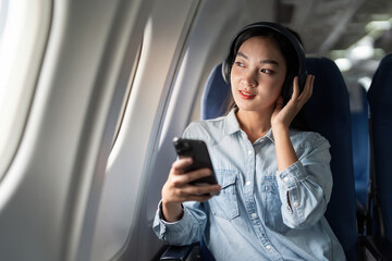 Young female listening song during flight in first class cabin using smartphone, woman entertain on...