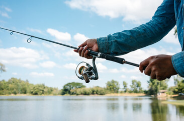 Woman holding fishing rod in her hands into the lake on sunny day.