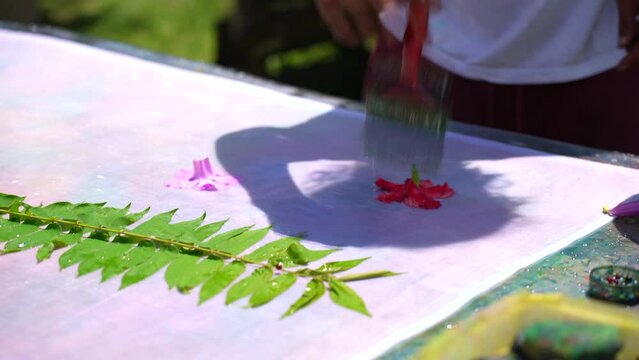 teaching homemade batik, sarong, pareo, Dark skin man wetting hibiscus flower on white cloth, Mahe Seychelles 25fps 2.