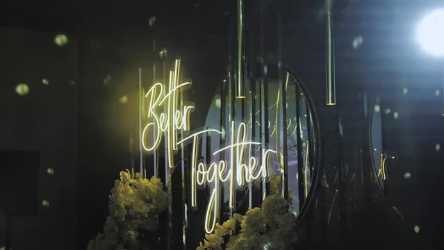 Neon glowing wedding lettering better together hanging on the wall light spots from disco ball, decoration for the wedding, neon lights.wedding decor slow motion.
