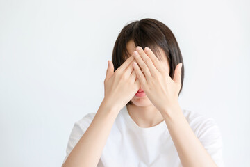 Thai woman covers her face with her own hands on a white background.