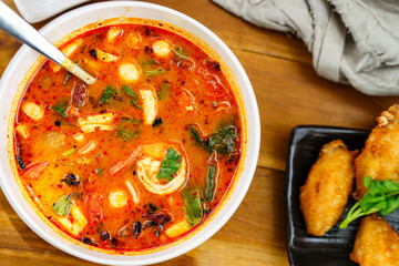 Shrimp tom yum in a white bowl on the dining table, top view.