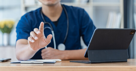 Asian male doctor with patient clipboard and laptop computer sitting at desk in hospital, Medicine and healthcare concept.