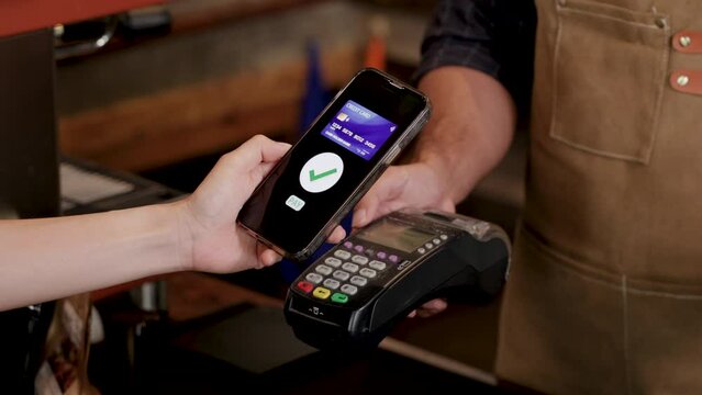 Unrecognizable hands of customer female using credit card to pay for goods or a cup of coffee in eatery cafe shop with cash register machine, technology cashless wireless transaction payment lifestyle