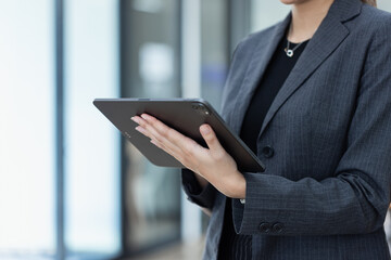 Portrait of Asian businesswoman using digital tablet standing in office workplace.