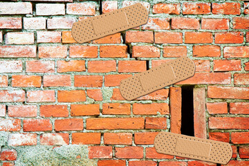 Renovation of an old cracked brick wall - concept with bandaid patch - obrazy, fototapety, plakaty