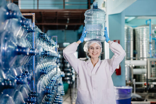 happy women worker working in drinking water plant factory with enjoy work with wate bottle gallon in warehouse with hygiene uniform.