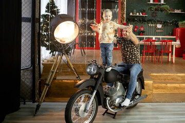 father and son play in a house decorated for the New Year. father and son play with a motorcycle....