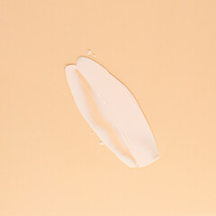 Smear of white cream for face and body on a brown background