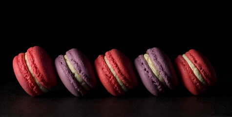 Colored macaroons. Delicious sweet colorful French desserts on black background.