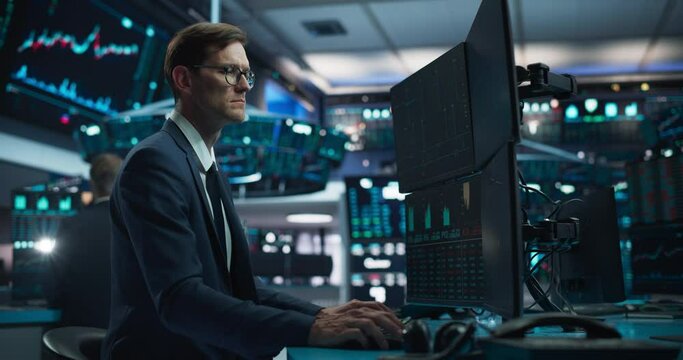 Portrait of a Young Handsome Stock Exchange Broker Working on Computer, Researching Real-Time Stocks Data, Analyzing Commodities and Exchange Market Charts. Professional Investment Agent in Office
