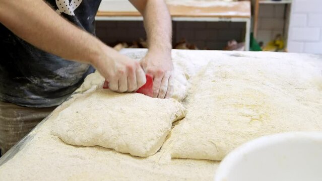 Skilled Worker Crafting Bread: Unseen Hands Expertly Weighing Dough Pieces in Bakery Workshop.