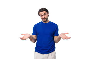 young brunette man with a beard dressed in a blue t-shirt thinks about solving problems on a white background