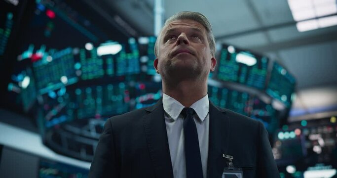 Portrait of a Handsome Adult Stock Exchange Broker Working in the Hall, Monitoring Real-Time Stocks Data, Analyzing Commodities and Exchange Market Charts. Professional Investment Agent in Office