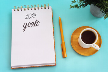 Top view 2024 goals list with notebook, cup of coffee on pastel background