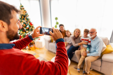 Multi-generation family taking photos while celebrating Christmas at home