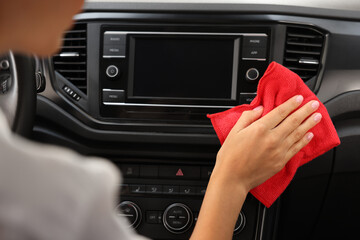 Woman cleaning center console with rag in car, closeup