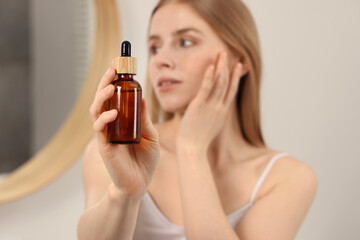 Fototapeta premium Woman with bottle of essential oil indoors, selective focus. Space for text