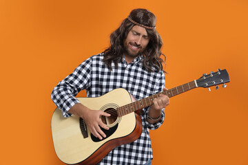 Hippie man playing guitar on orange background