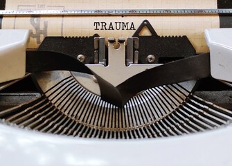 Vintahe typewriter with text typed TRAUMA -  person's emotional response to a distressing...
