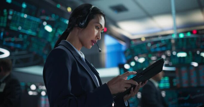 Professional Stock Exchange Trader Working with Serious Focused Attitude. Female Stockbroker Talking with Business Clients on a Call, Working on Tablet, Day Trading Shares for Business Clients