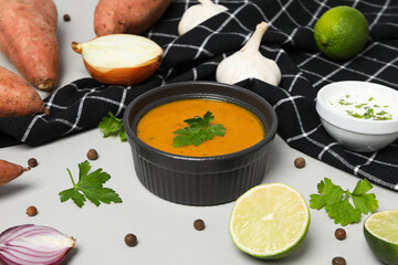 Sweet potato puree in bowl, towel and ingredients on white background