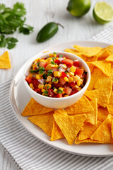 Homemade Corn Salsa with Tortilla Chips on a Plate, side view.