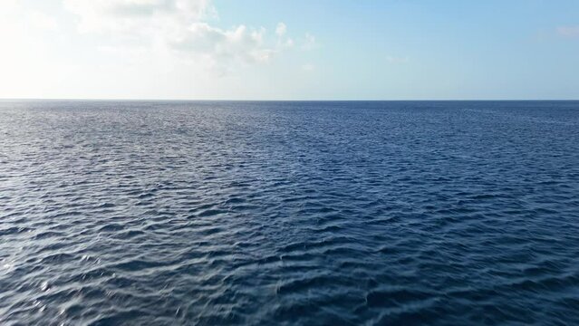 Aerial dolly forward above deep vibrant mysterious blue ocean water in Caribbean