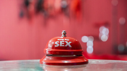 Sex call and sex education concept with reception ring bell in sex shop blur background and blurred sexy red erotic bed room for adult escort service business and men club