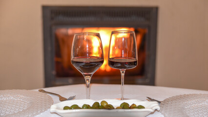 Red wine next to a fireplace, cozy and relaxing atmosphere in the country house and vacation time background. Luxury rest concept