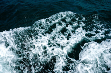 White foam in the sea from a sailboat.Blue water of different shades in the ocean mixed with white...