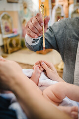 Baptism ceremony of baby. Closeup of tiny baby hand, the sacrament of baptism. Godmother holds...