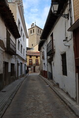 Fototapeta na wymiar Cebreros, Avila, Spain, November 28, 2023: Narrow street with the church bell tower in the background of the town of Cebreros, Avila, Spain