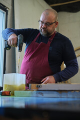 A craftsman mixes resin, a step in modern woodworking. Resin art's popularity reflects a blend of...