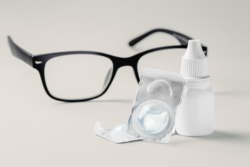 Contact lens with solution and eyeglasses on beigebackground
