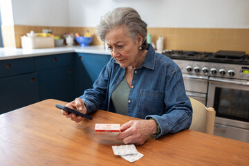 Senior woman at home using a smartphone to read about medication