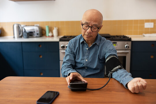 Senior man measures his blood pressure at home